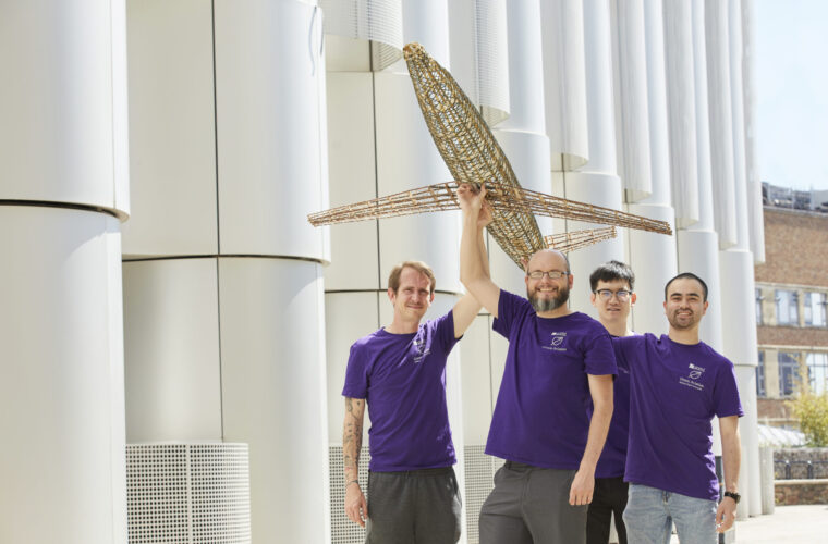 Four people holding an aircraft model that they have built. They are smiling.